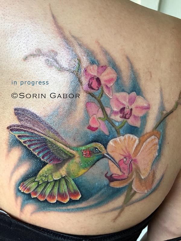 realistic color hummingbird and orchids tattoo by Sorin Gabor Tattoos